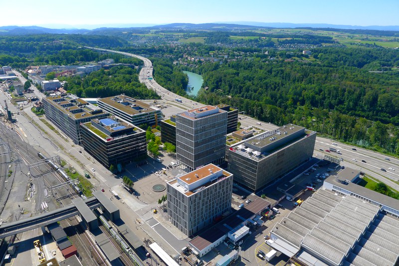 Das Bild zeigt eine Luftaufnahme von WankdorfCity. In der Mitte dominieren die modernen Bürogebäude, im Hintergrund sind Autobahn und Aare zu sehen.