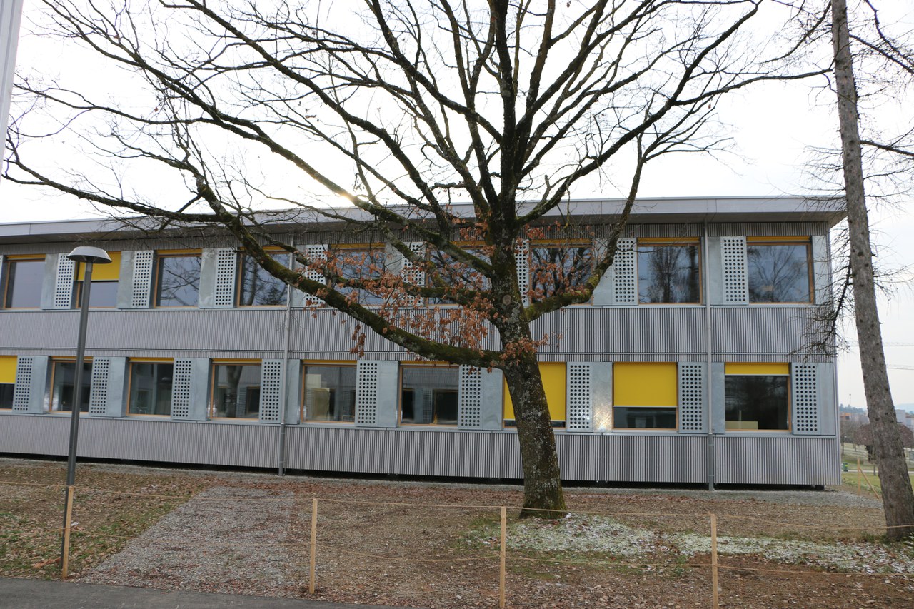 Das Bild zeigt ein graues Schulgebäude.
