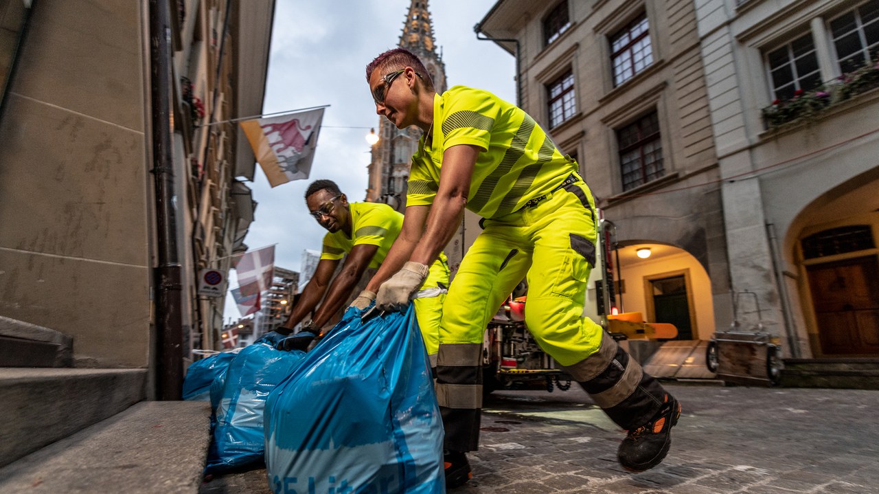 Zwei Mitarbeitende laden Kehrichtsäcke in den Kehrichtwagen