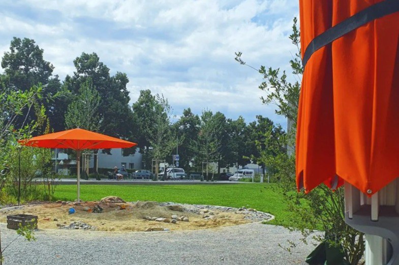 Orange Sonnenschirme sind auf dem Spielplatz verteilt.