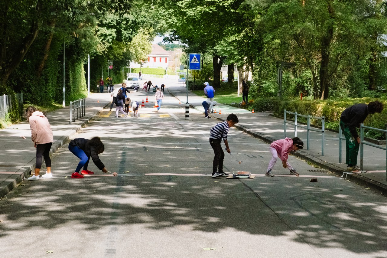 Kinder bemalen die Keltenstrasse mit Kreide. @atelier OLGa, Philéas Schulhof