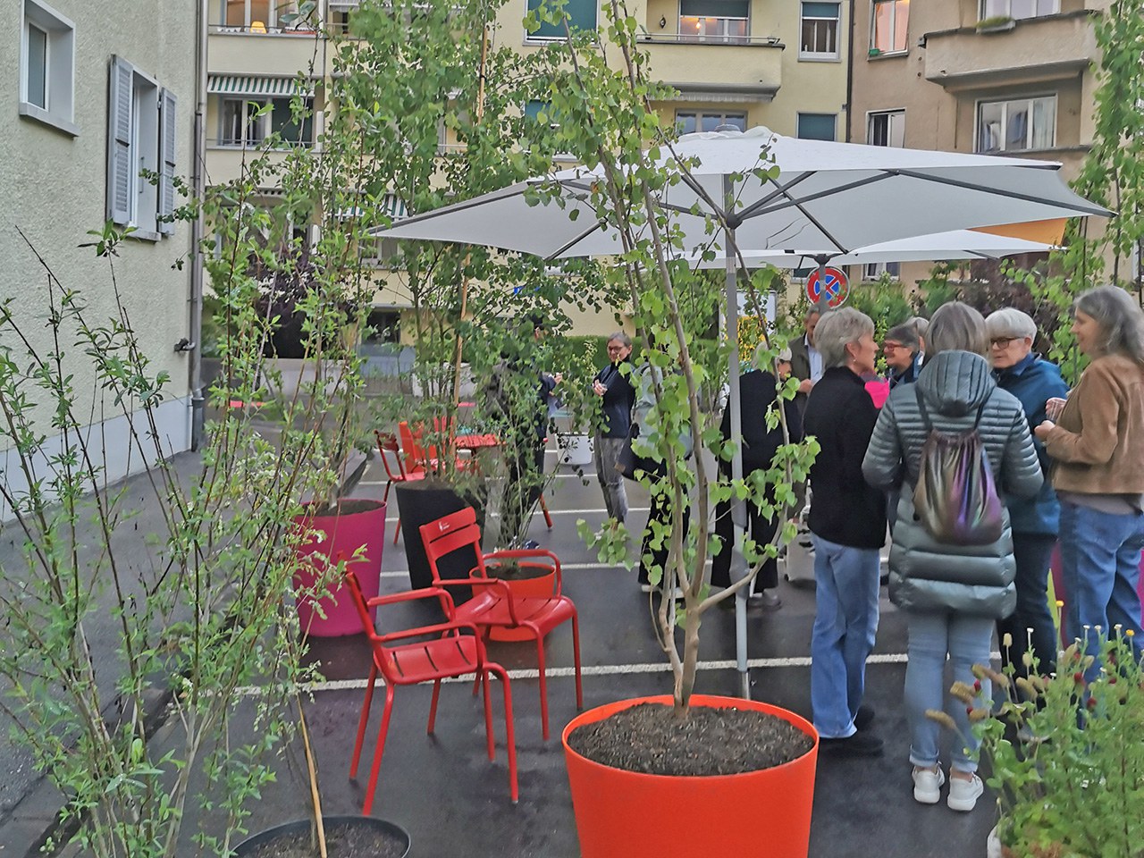 Pflanzen dekorieren die Gegend. Im Hintergrund reden die Anwohnenden